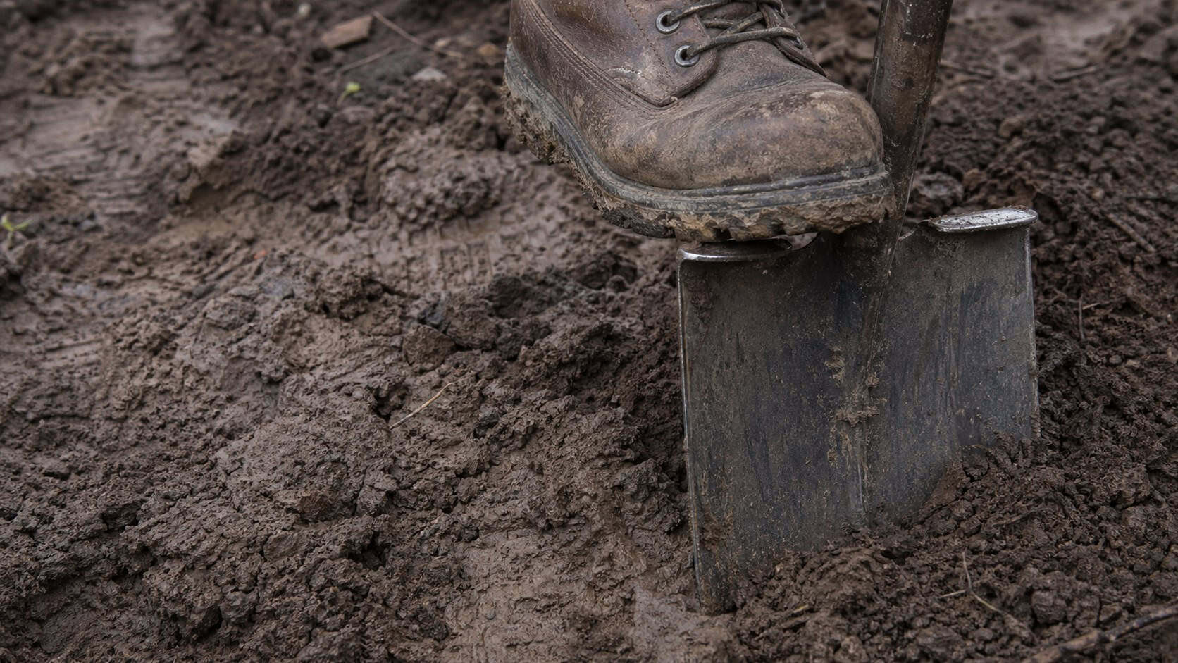 Worn boot on a shovel pressed into damp Northeast Ohio soil during a Cuyahoga Falls, OH service call