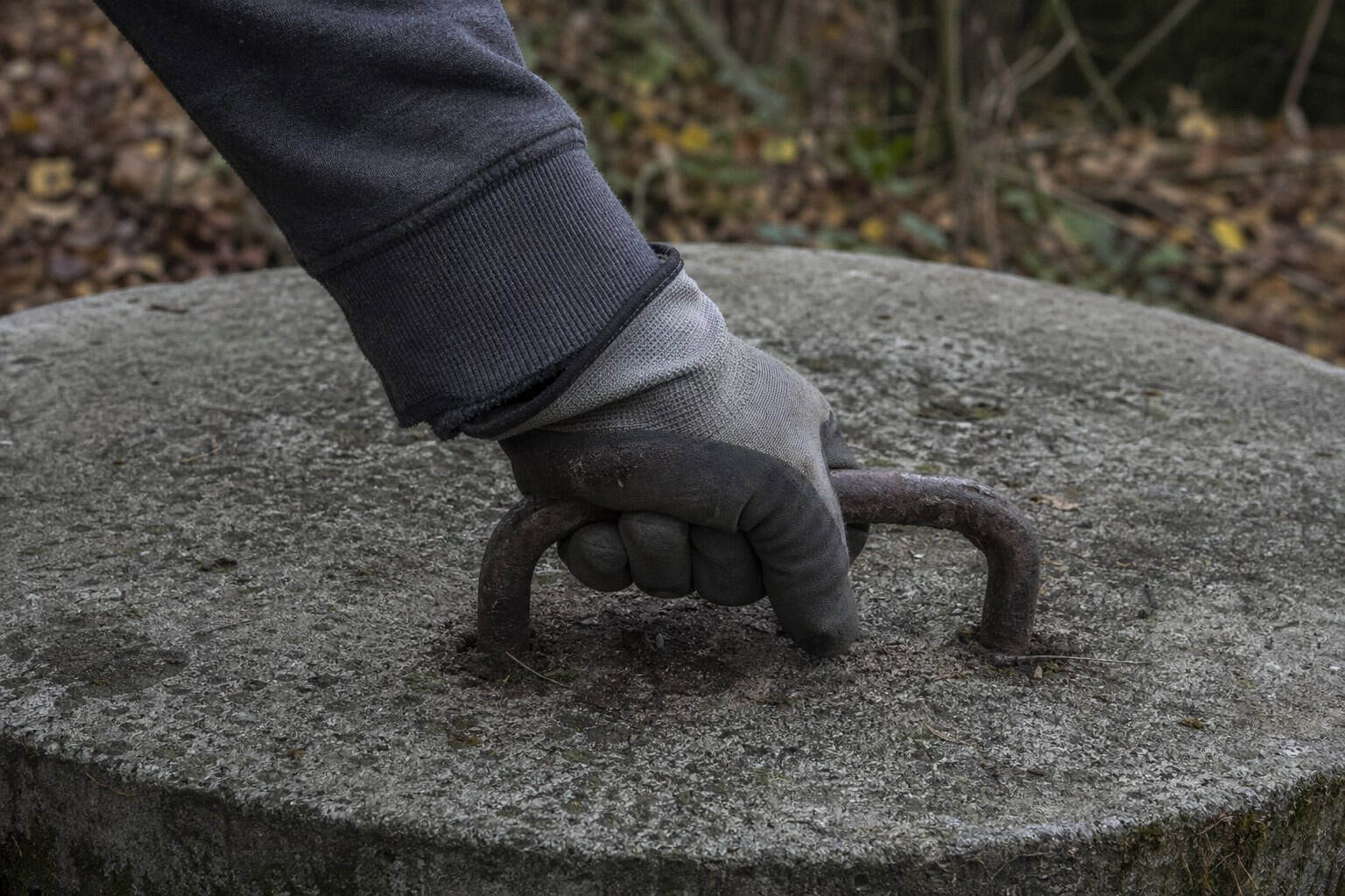 Gloved hand grabbing a concrete septic tank lid handle during a Peninsula, OH septic inspection