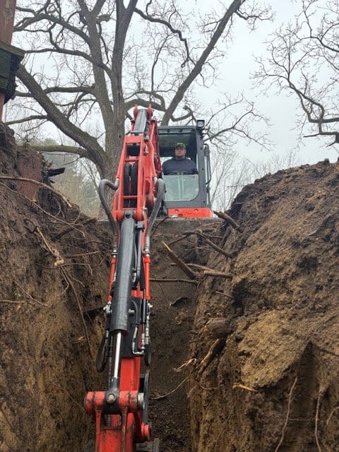 Septic tank repair excavation: excavator digging a deep trench in Northeast Ohio Septic tank repair excavation: excavator digging a deep trench in Northeast Ohio
